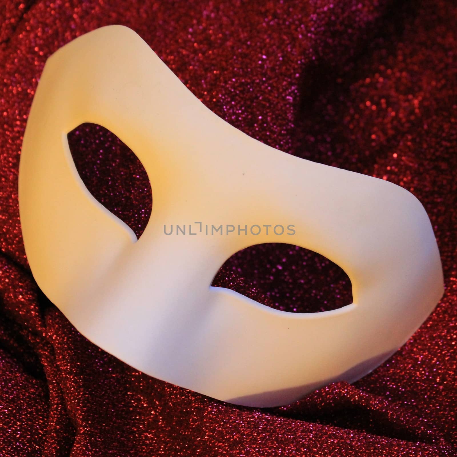 White canival mask on red glitters