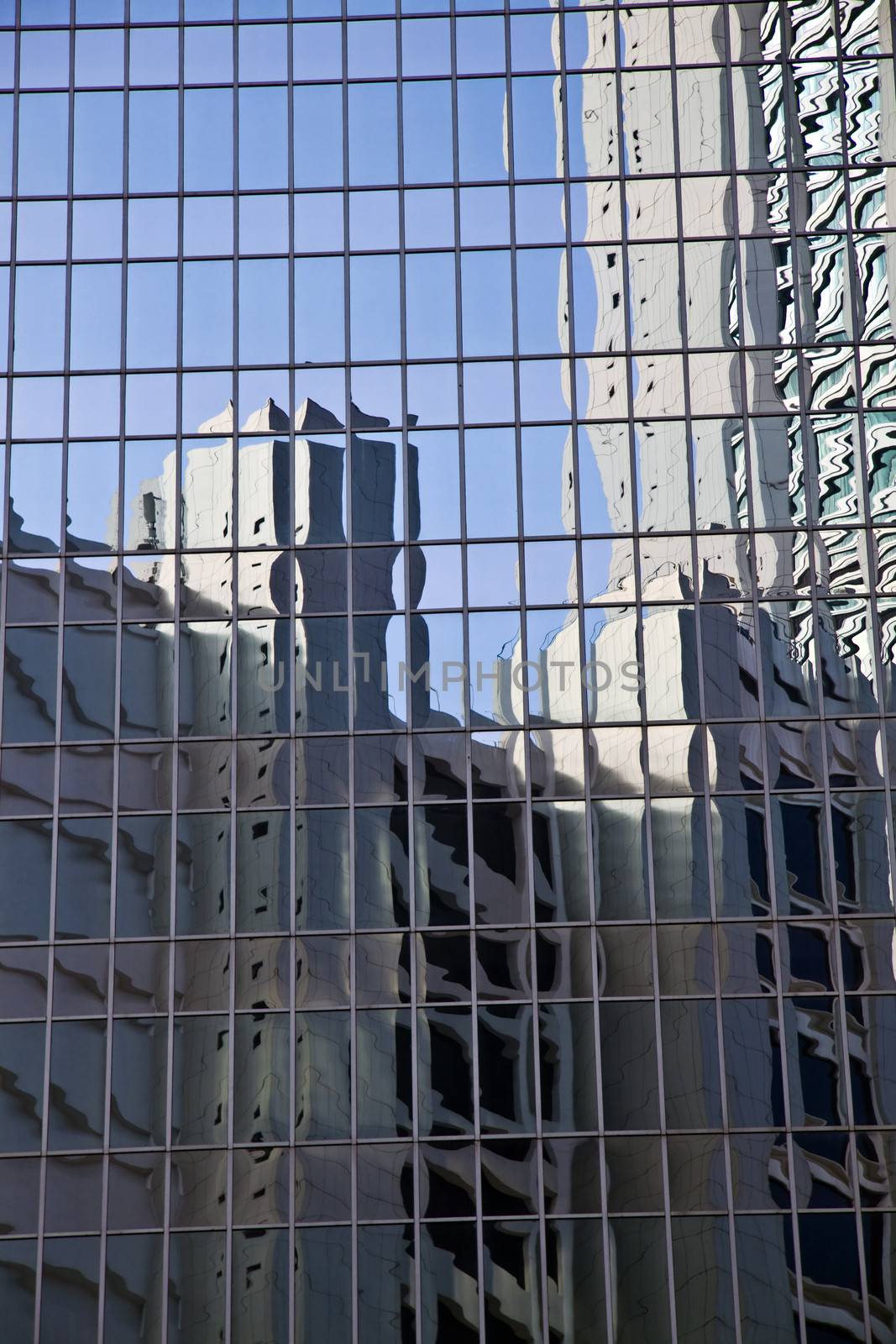 Glass wall with the reflection of blue sky and buildings