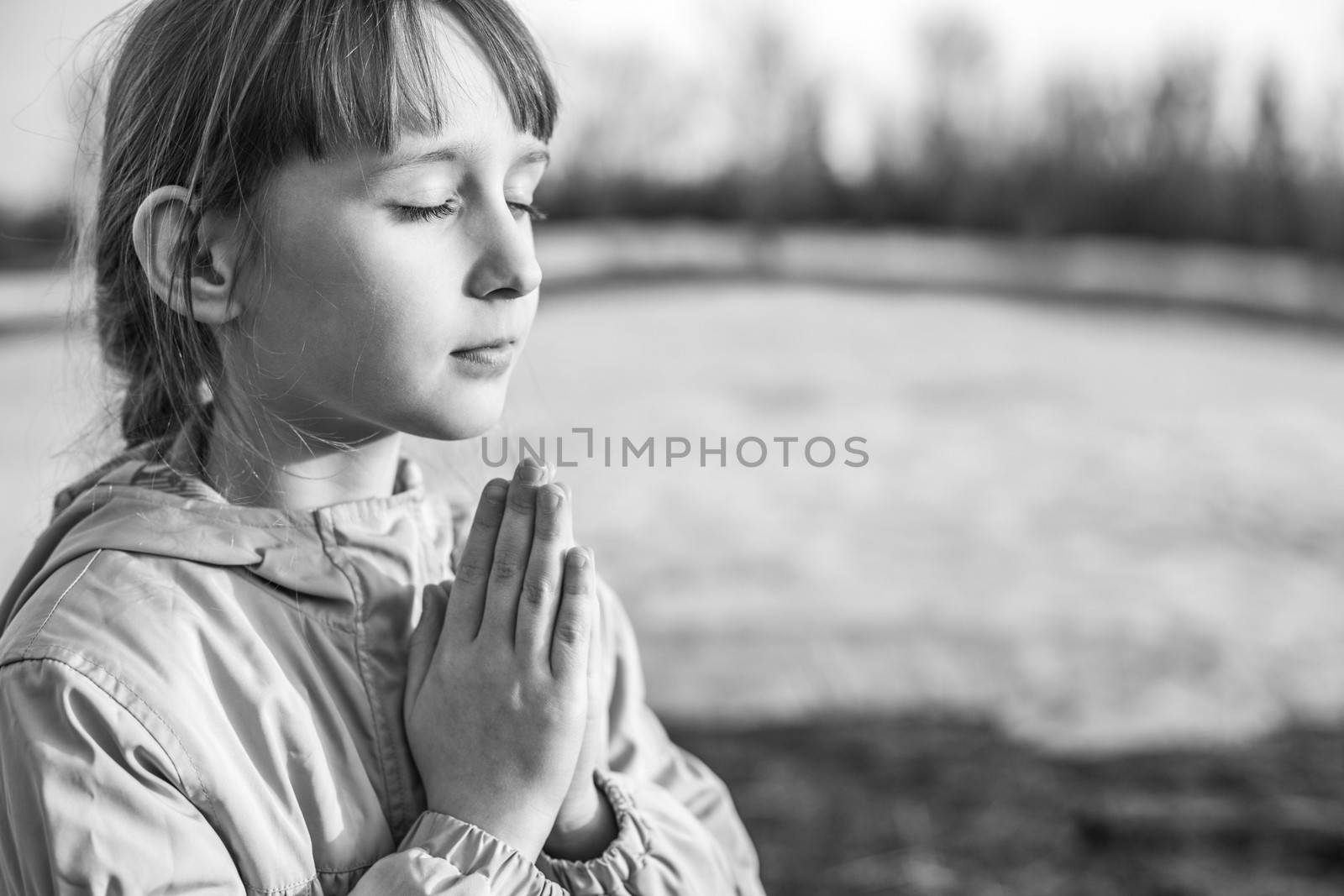 Young girl praying on the background of nature