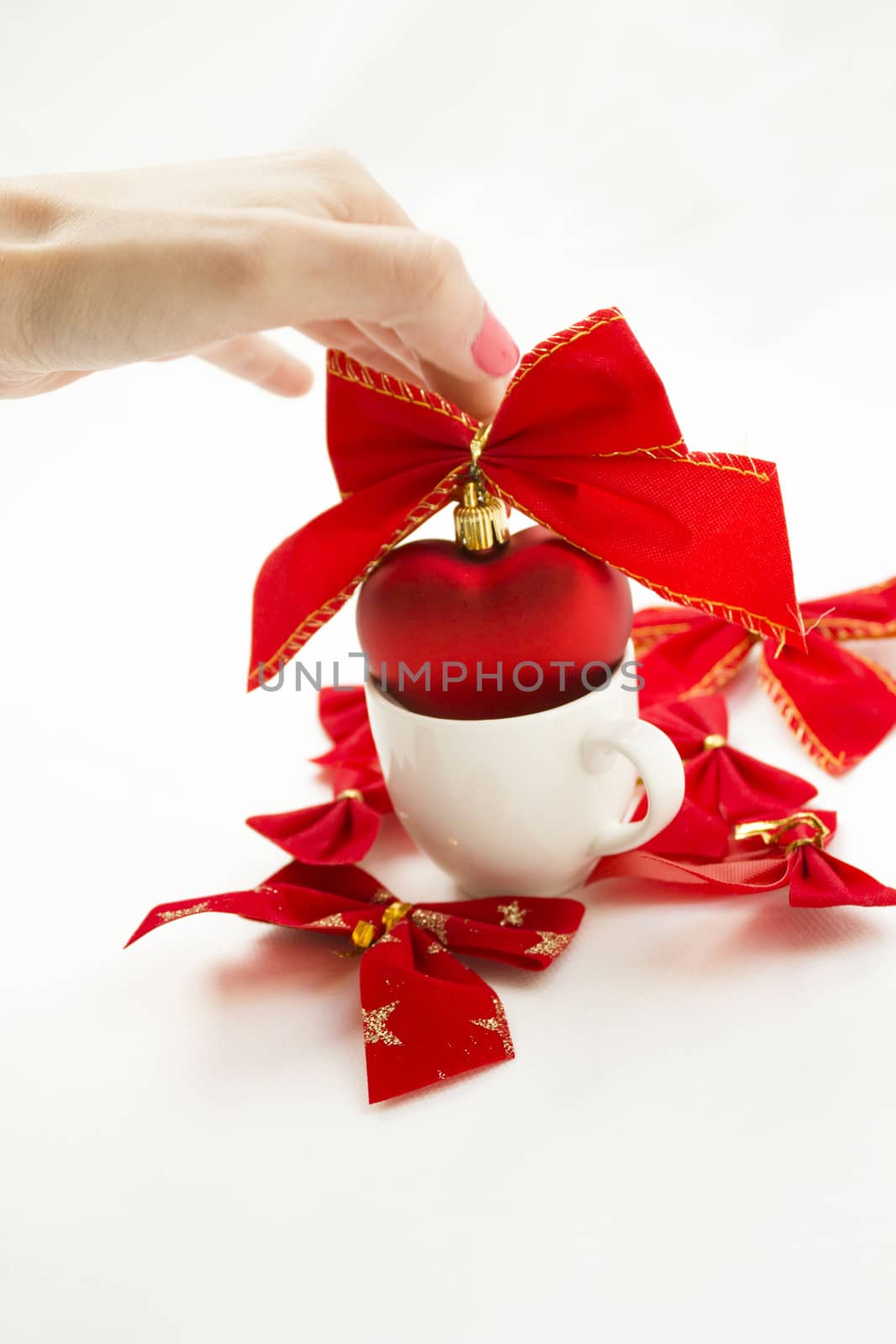 Cup with a heart in it tied with a ribbon. Other ribbons on the background are spread around.