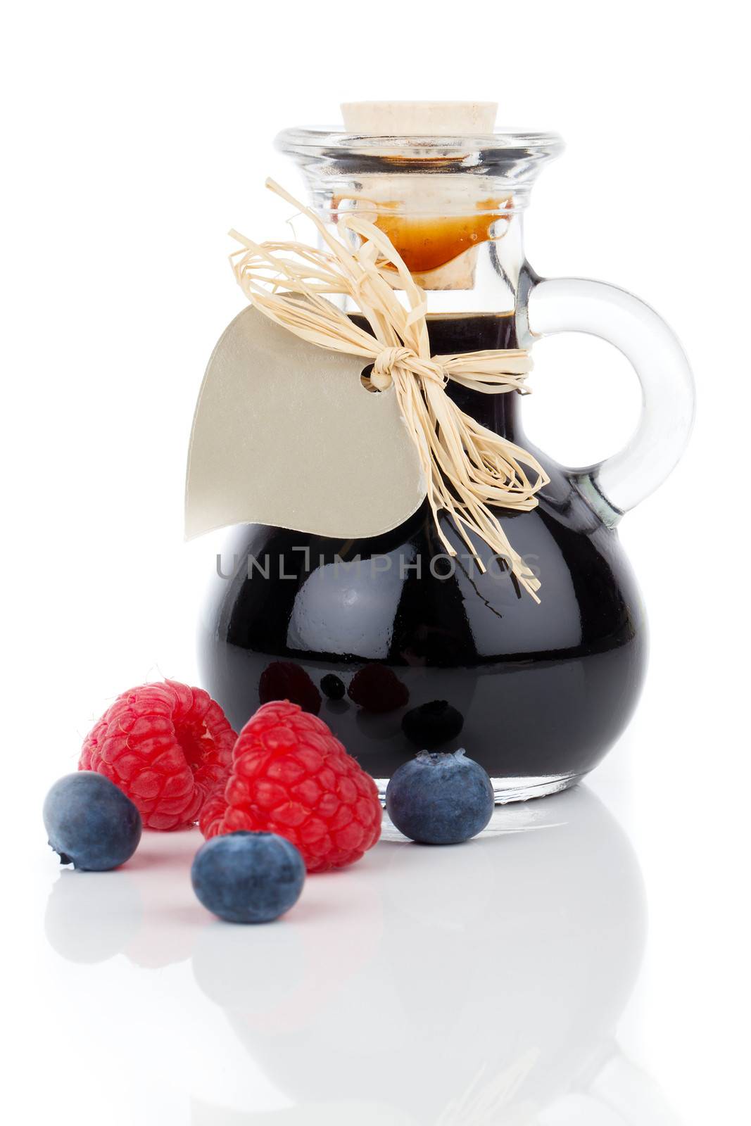 blueberry - raspberry syrup in glass bottle or mixture, with heart label. on white background.