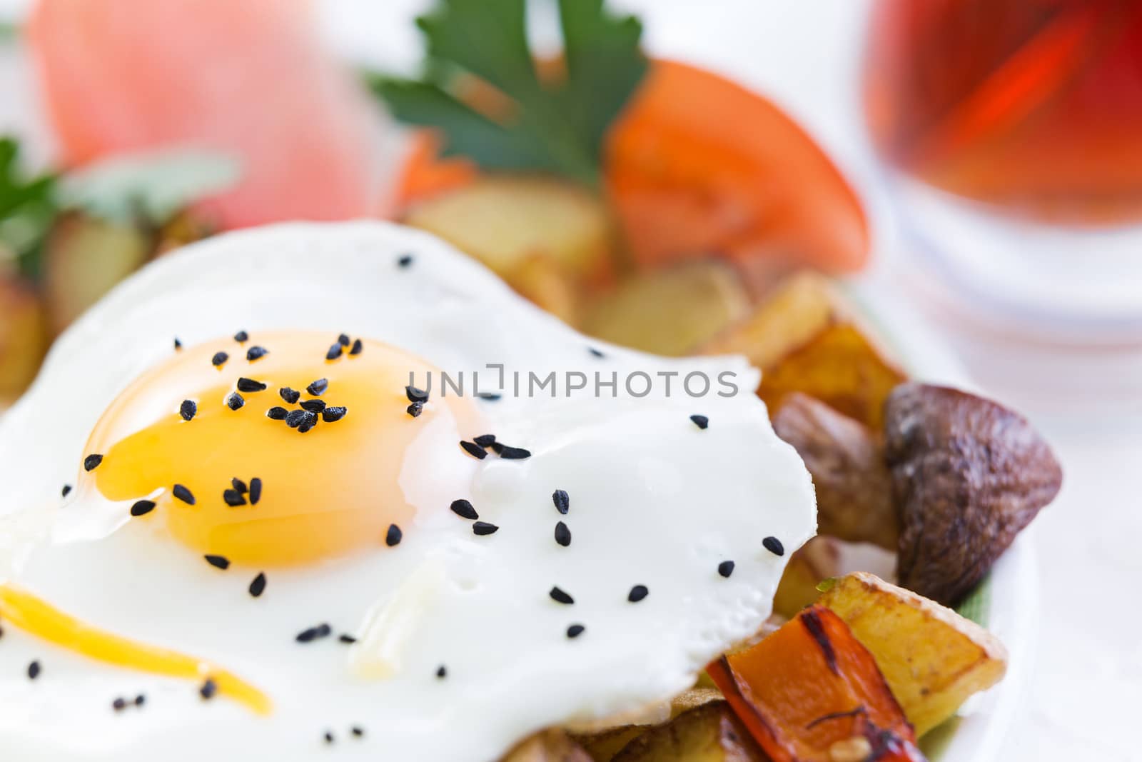Nutritious fried egg served sunny side up with healthy fresh vegetables including diced potatoes and mushrooms with tomato garnished with fresh parsley