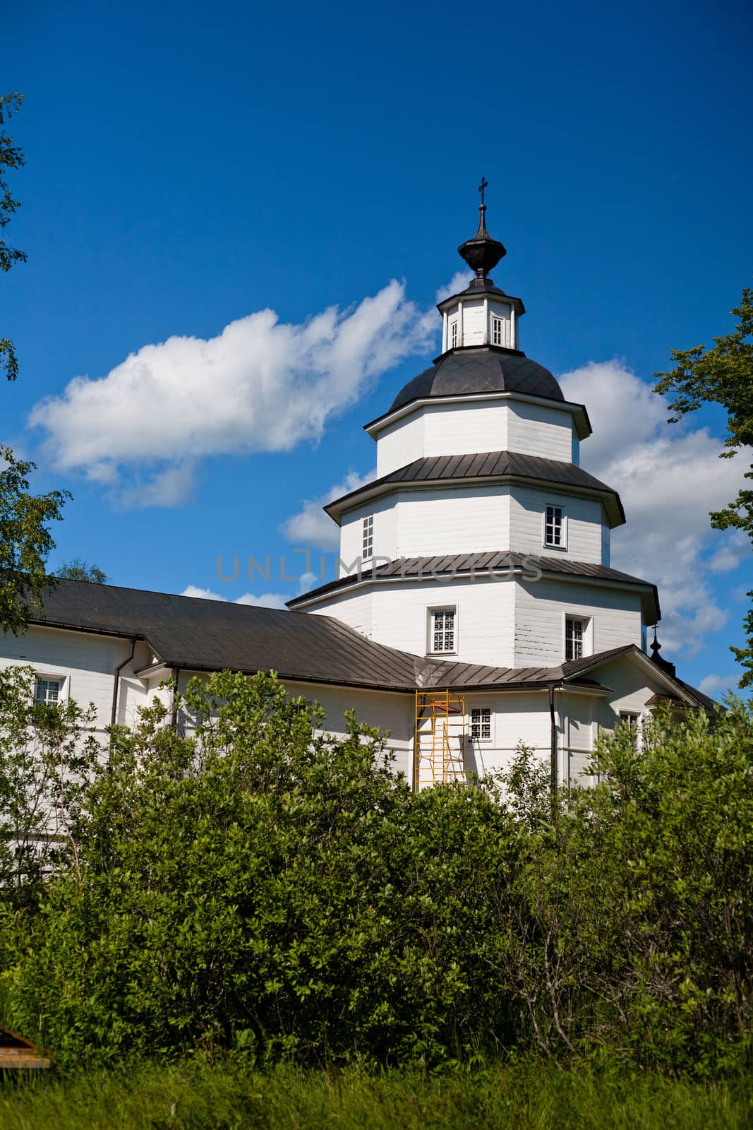 White orthodox church in a garden in summer day
