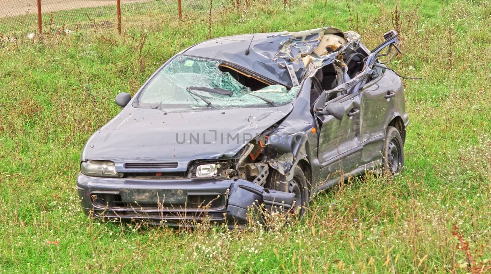 Hard crashed car in a field.