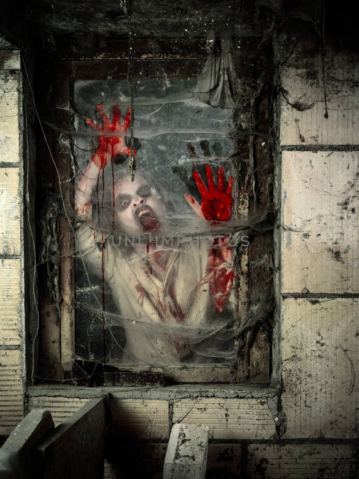 Photo of a hungry zombie covered with blood at the window.