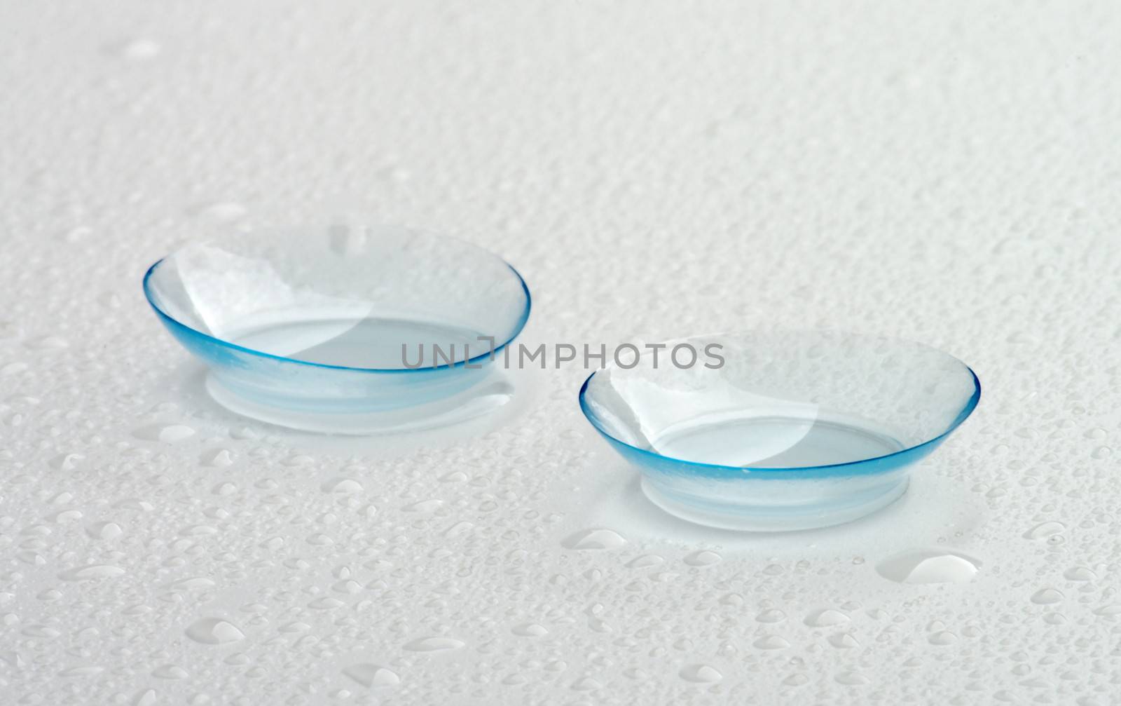 Two Contact Lenses with Water Droplets isolated on Grey Wet background