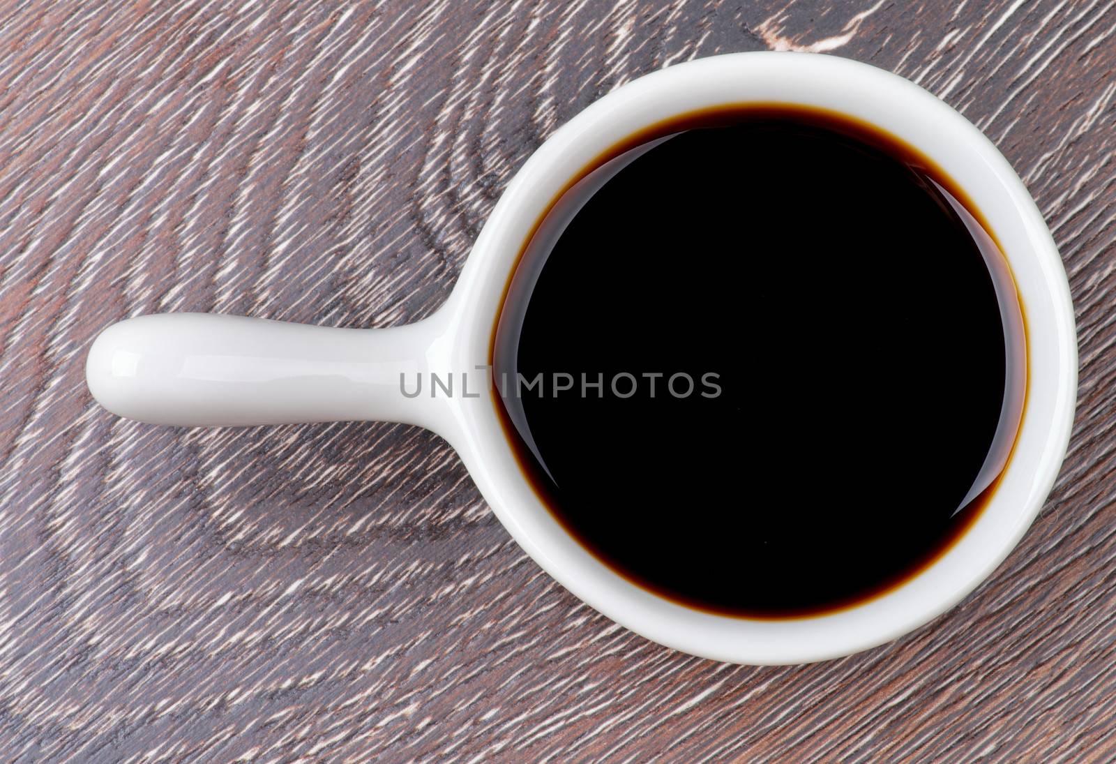 Soy Sauce in White Gravy Boat isolated on Wooden background. Top View