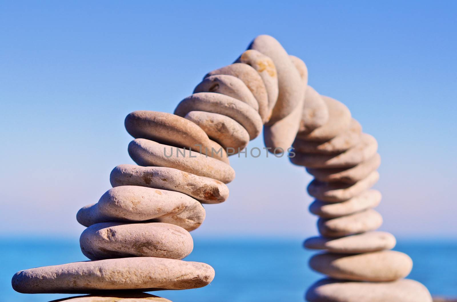 Arch of white pebbles on sky background