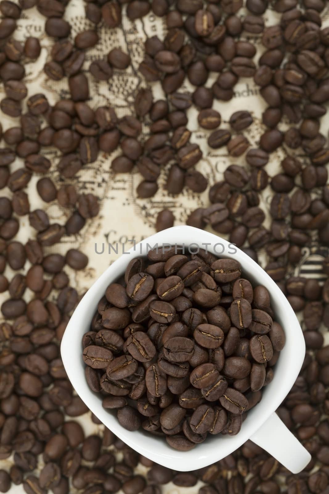 Cup full of coffee beans on the old map