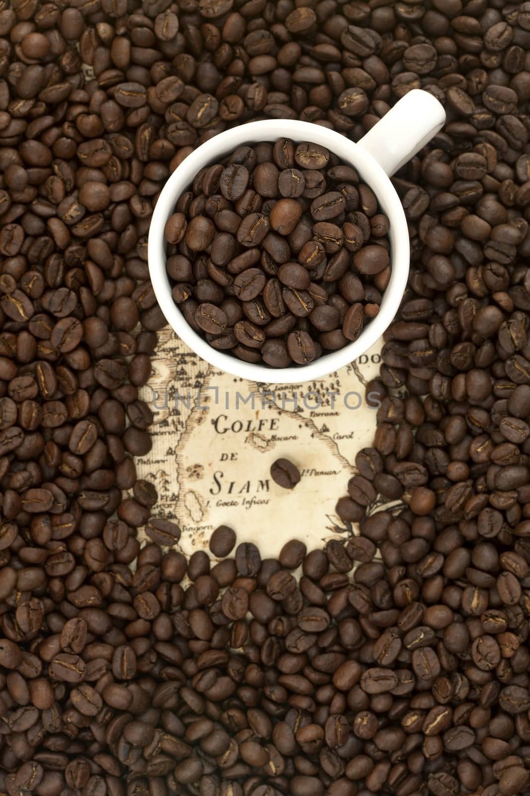 Cup full of coffee beans on the old map