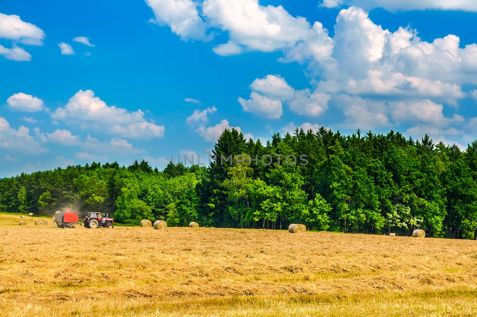 Tractor working in field among the haystacks