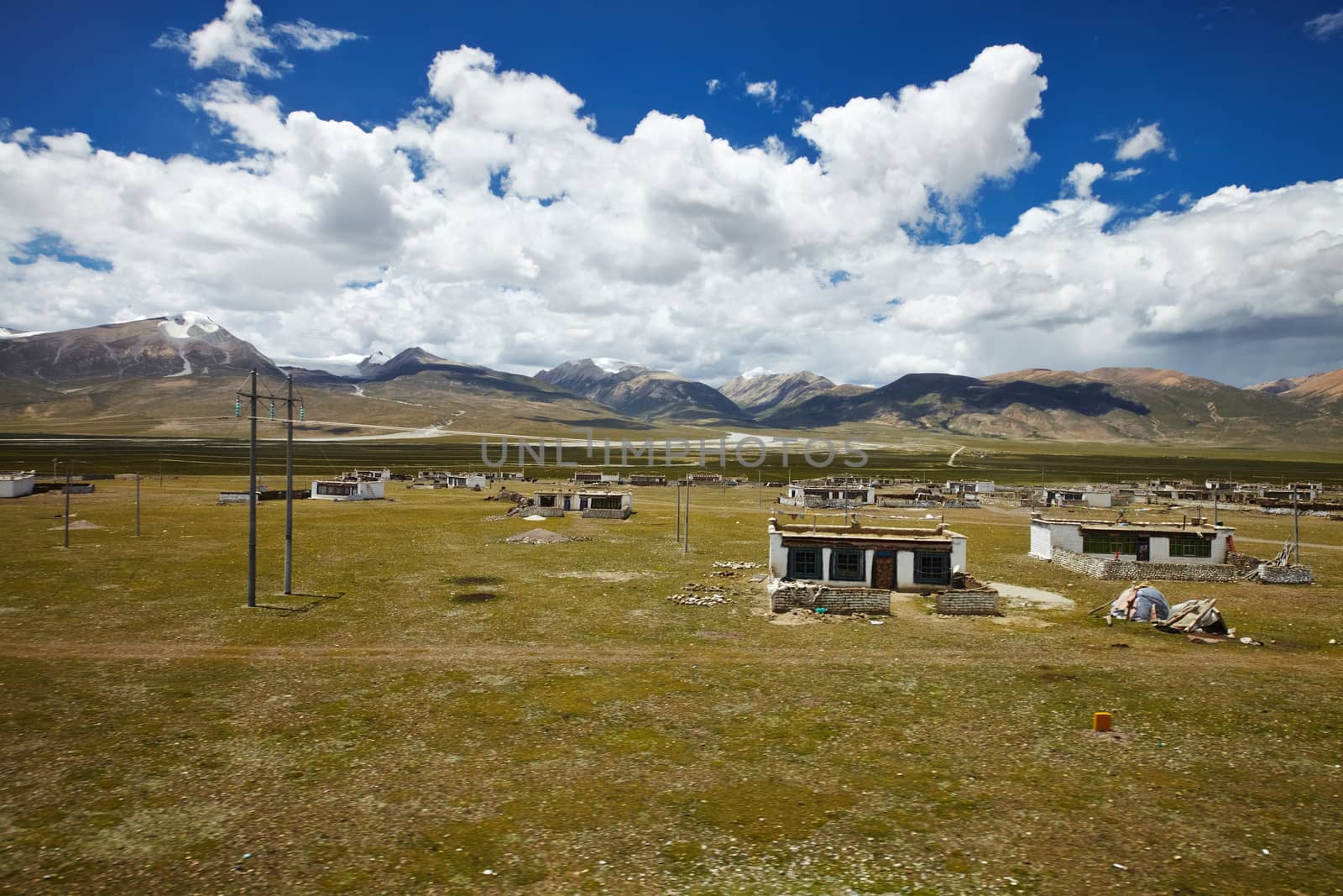 A Tibetan rural village in the outskirts. Snow capped mountain landscape with cloudy sky