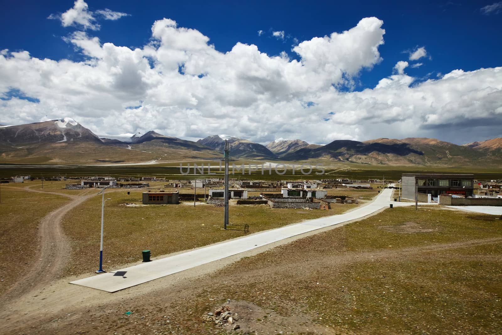 A Tibetan rural village in the outskirts. Snow capped mountain landscape with cloudy sky