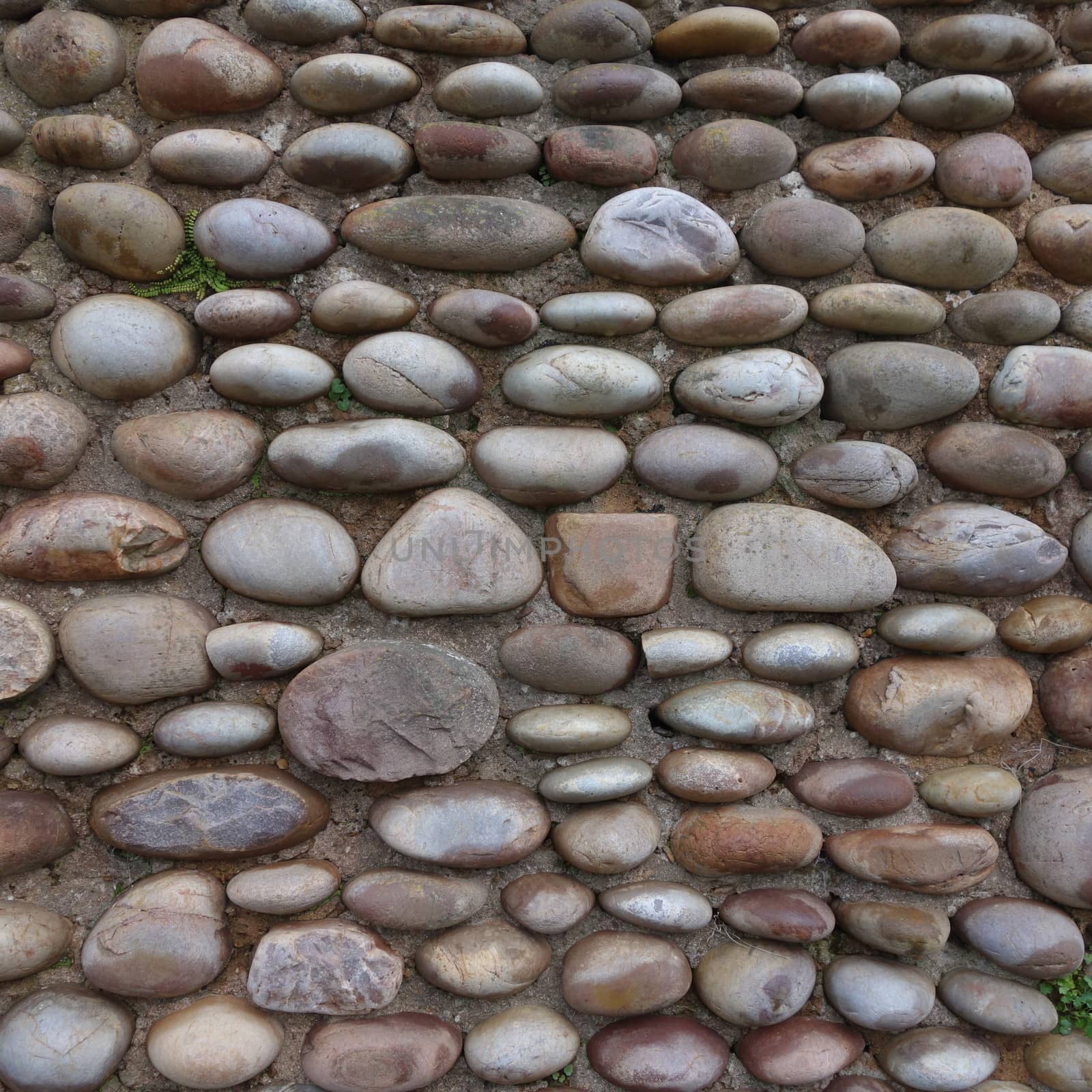 Square section of wall made of different shaped rounded pebbles