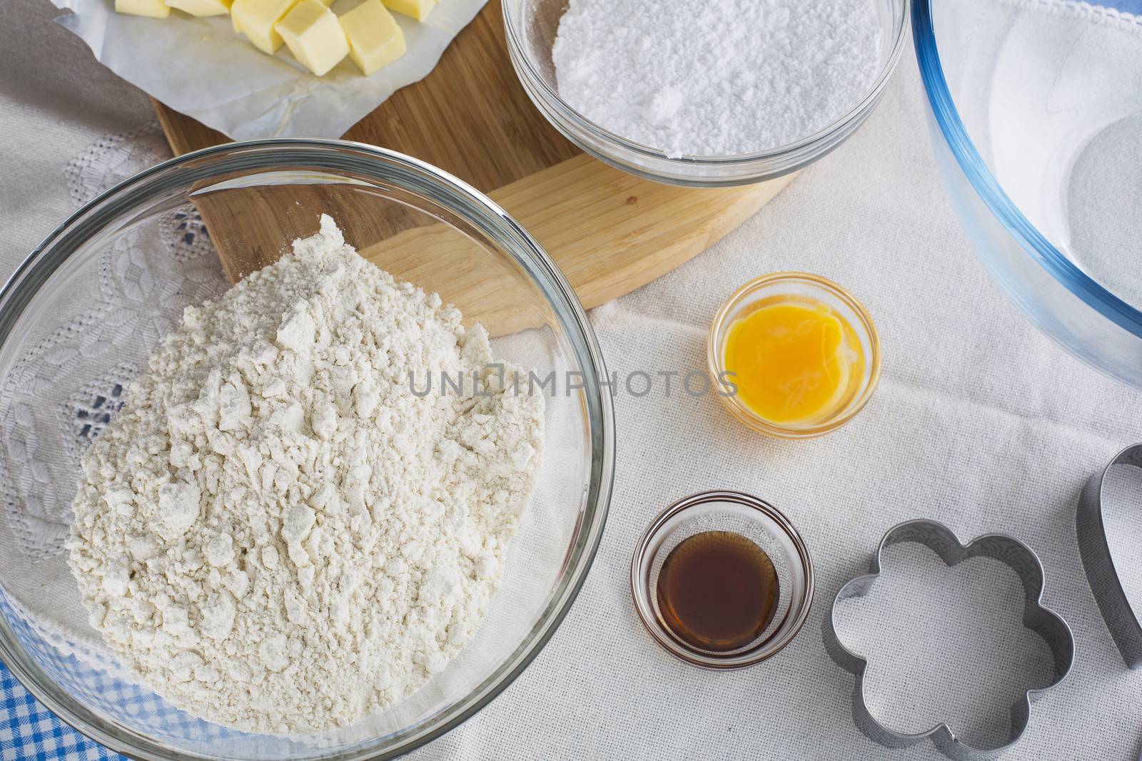 Baking ingredients including flour, egg yolk and vanilla extract, with cookie cutter.
