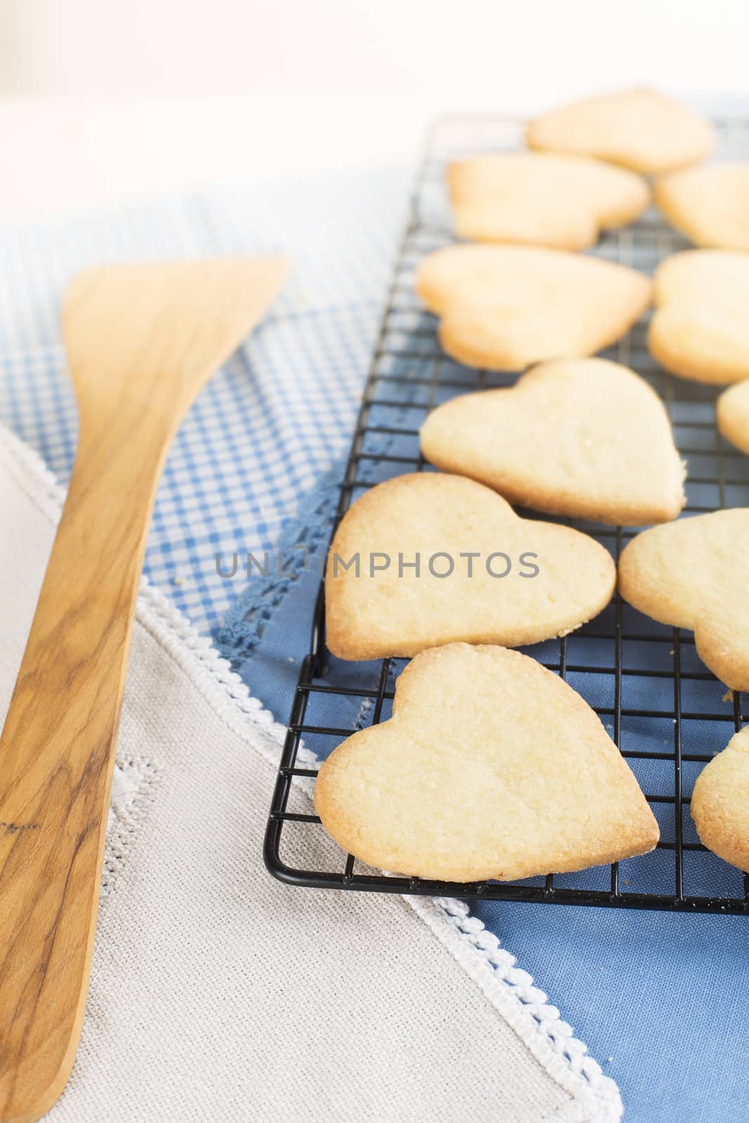 Fresh baked heart shaped cookies on cooling rack.