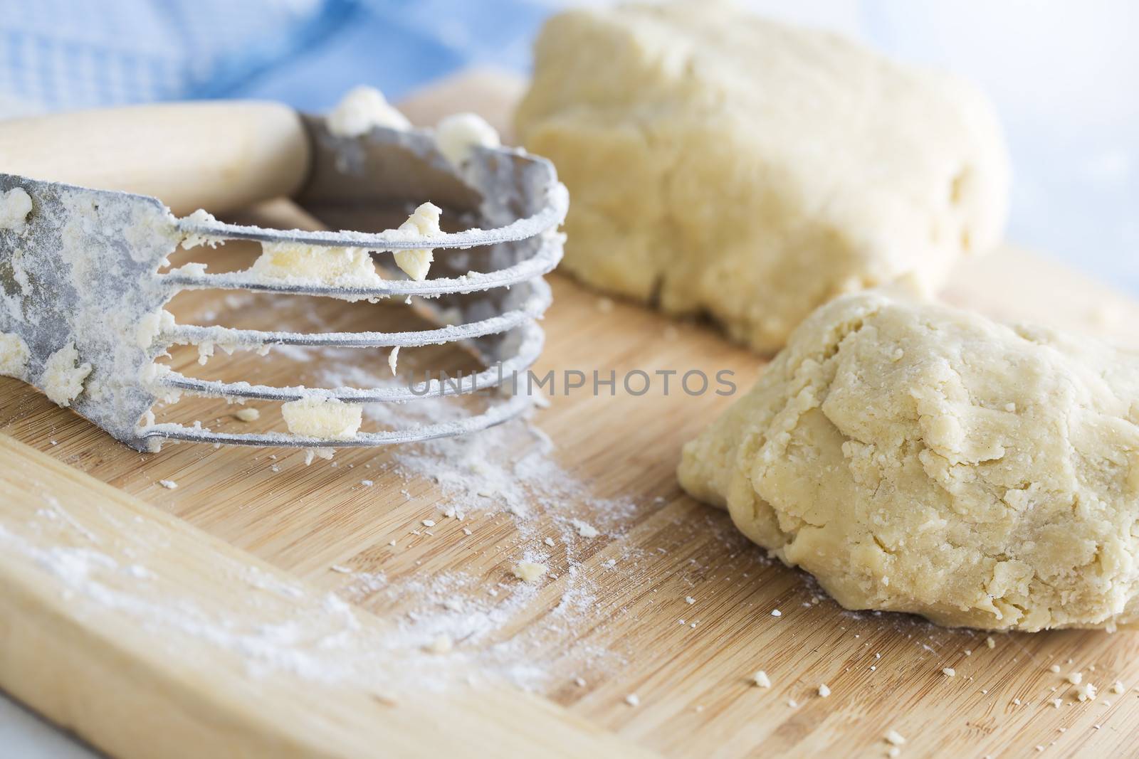 Dough and handheld pastry blender on cutting board.