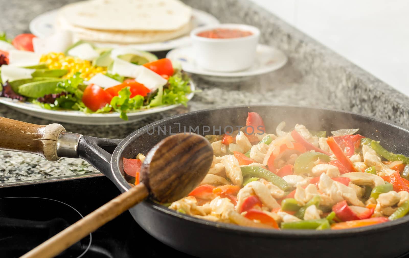 Closeup of black pan cooking vegetables and chicken for a mexican food in the kitchen