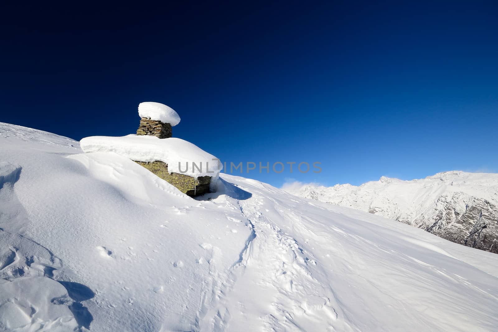 Winter landscape with weird rocky boulders covered by thick windswept snow.