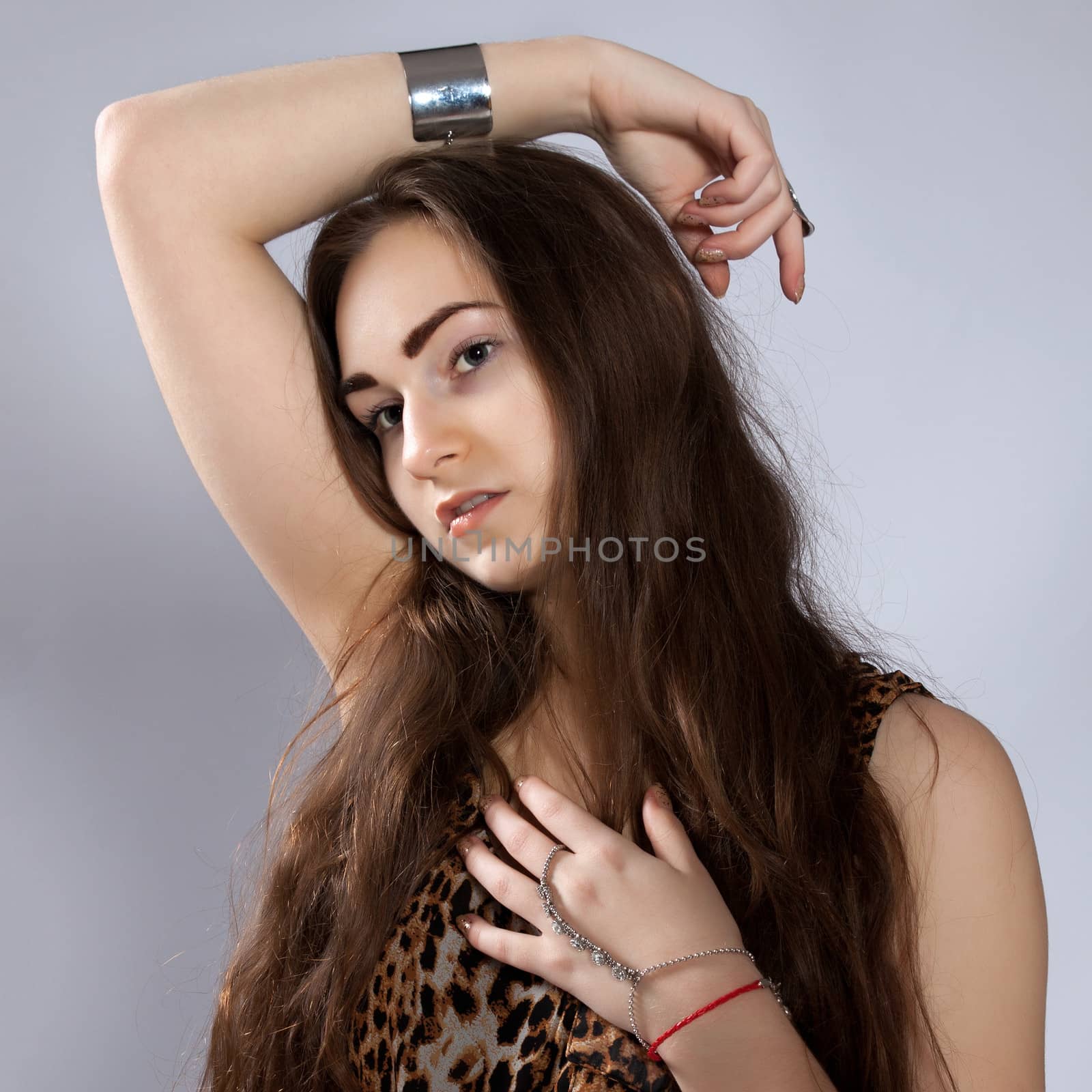 Portrait of long-haired teenager girl in leopard dress has a hand resting on the head and one to the chest