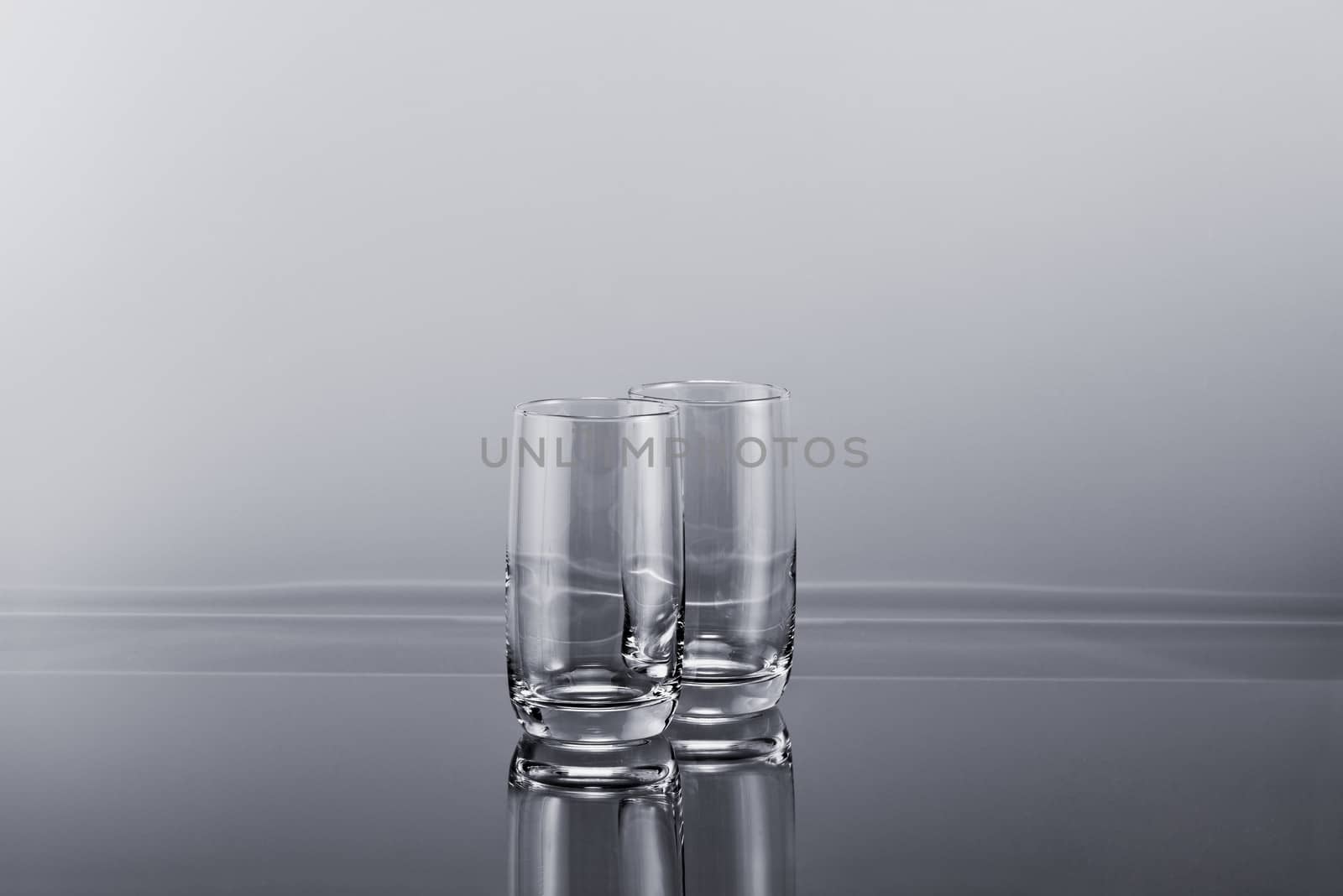 Two transparent empty tall glasses on a gradient simple background