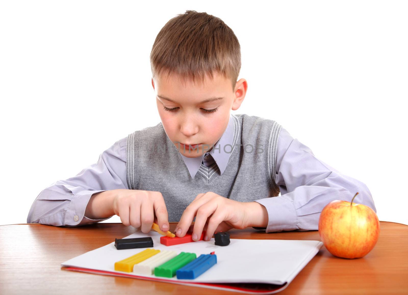 Cute Kid playing with colorful plasticine at the School Desk