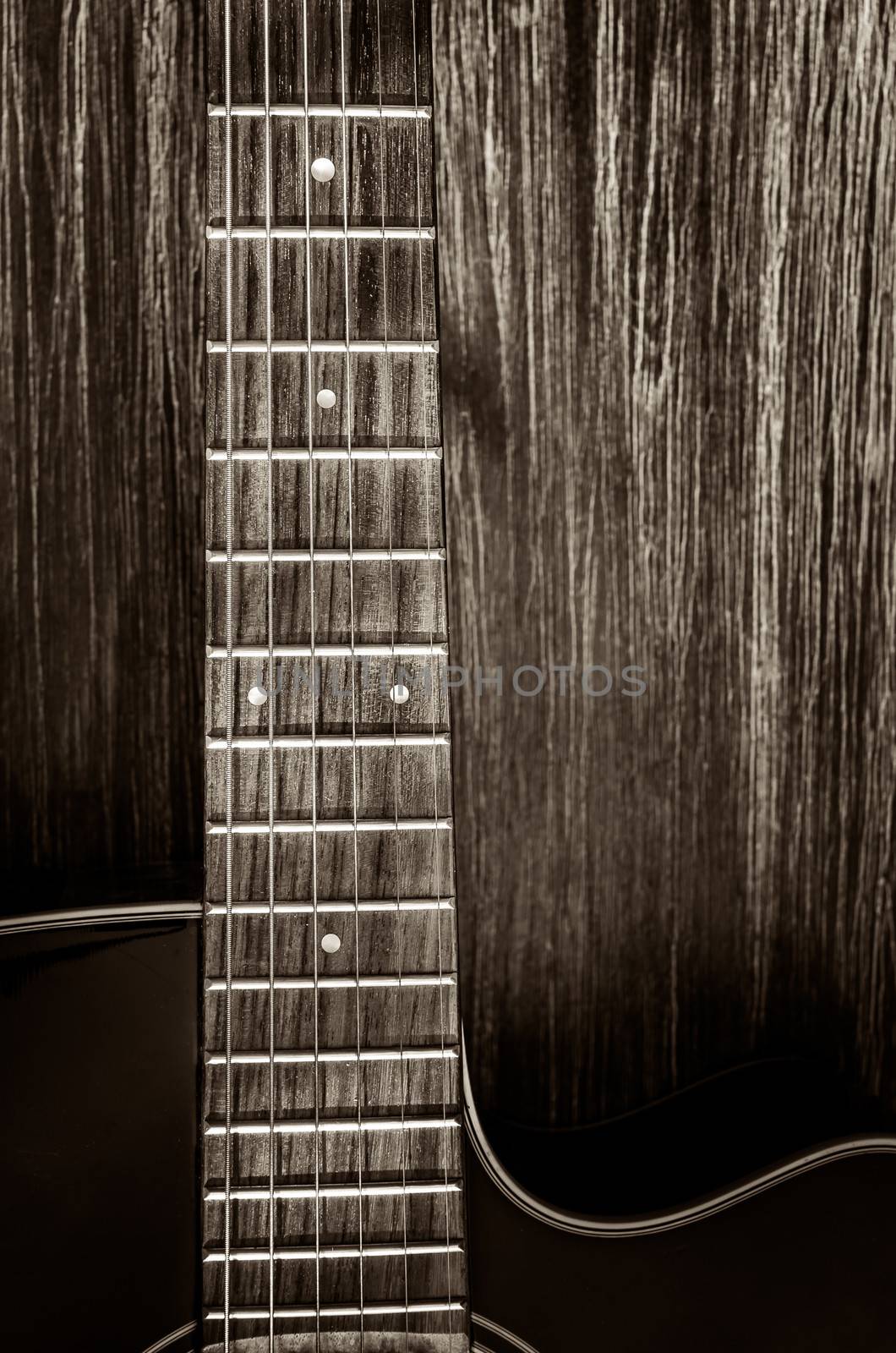 Detail of acoustic guitar in vintage style on wood background by martinm303