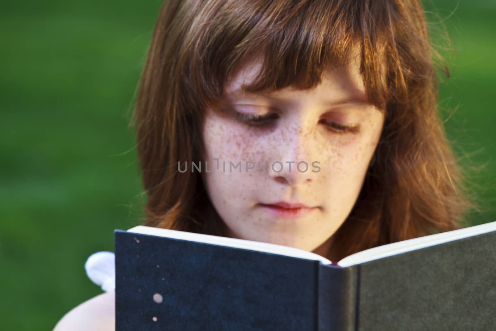 Young beautiful girl reading a book outdoor by FernandoCortes