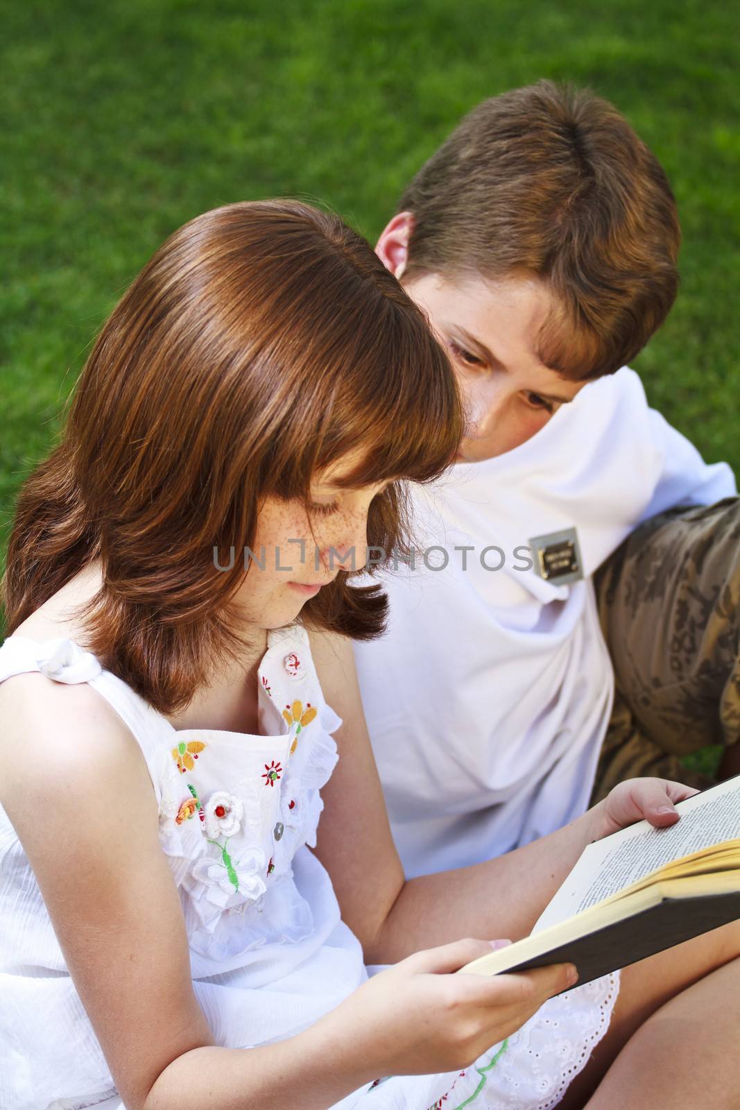 Portrait of cute kids reading books in natural environment by FernandoCortes