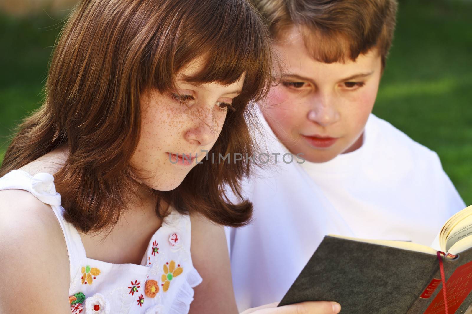 Portrait of cute kids reading books in natural environment by FernandoCortes