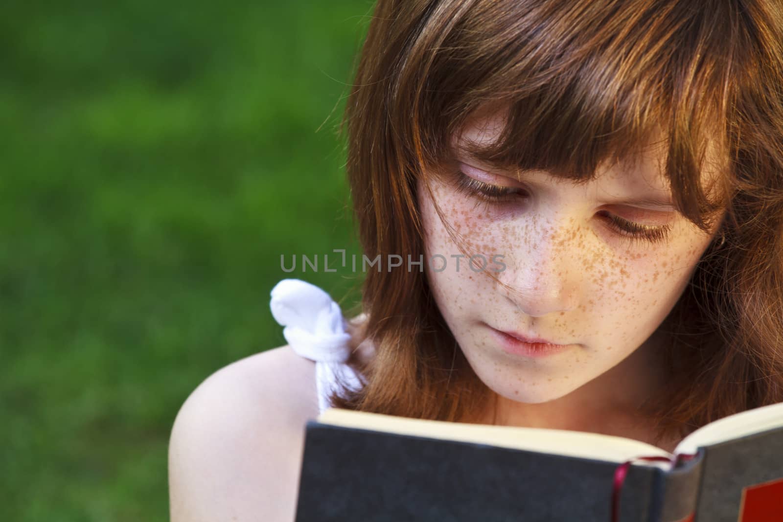 Young beautiful girl reading a book outdoor