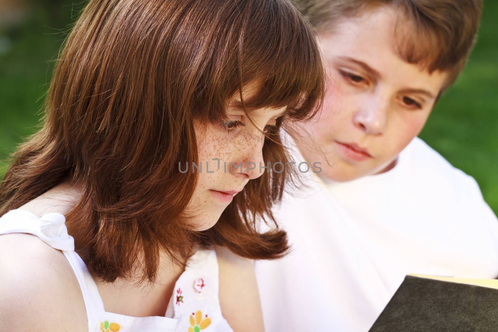 Teenagers.Portrait of cute kids reading books in natural environment