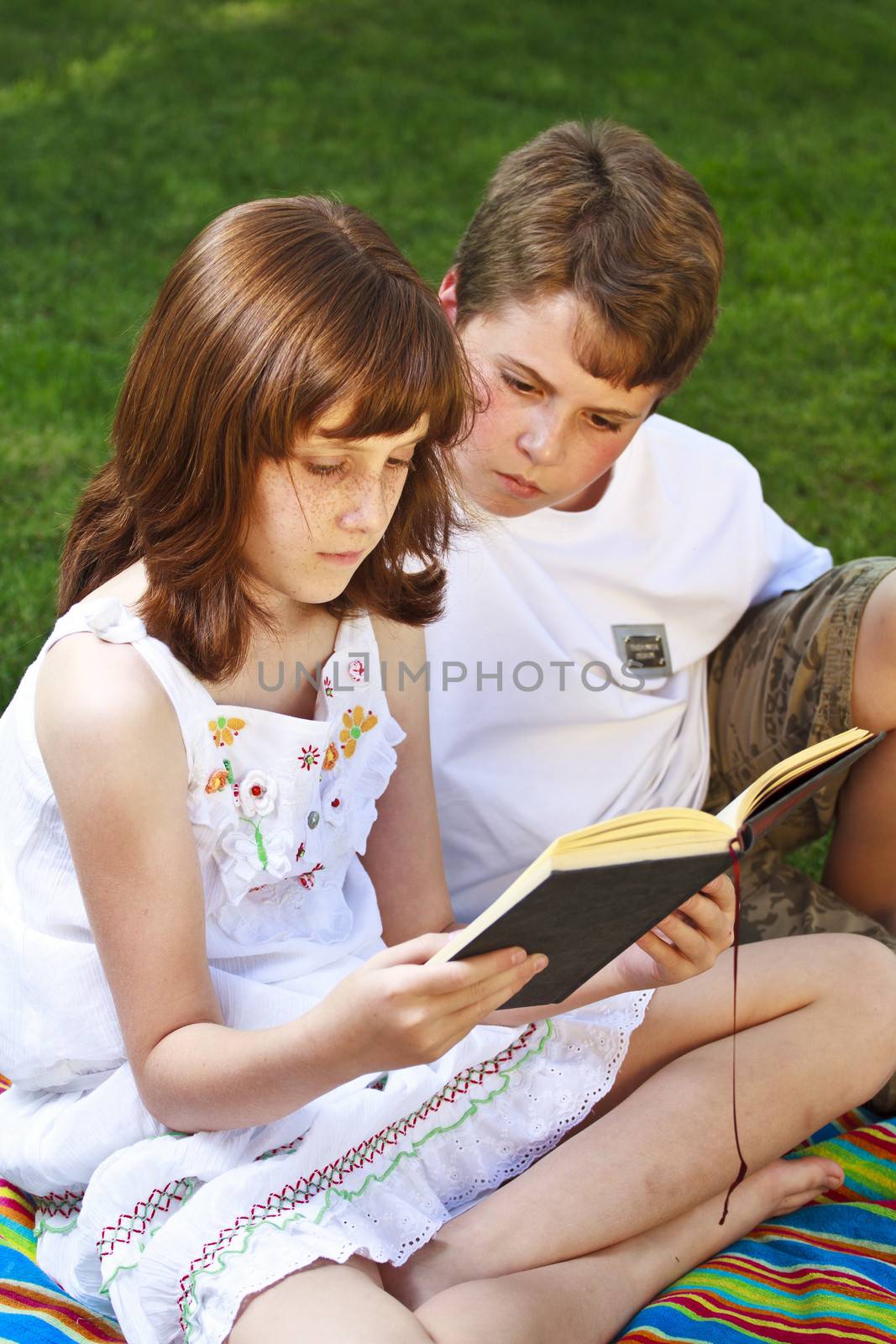 Teenagers.Portrait of cute kids reading books in natural enviro by FernandoCortes