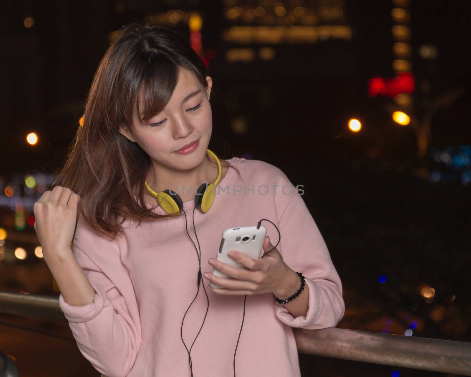 Beautiful Asian woman with smart phone and yellow headphones  by imagesbykenny