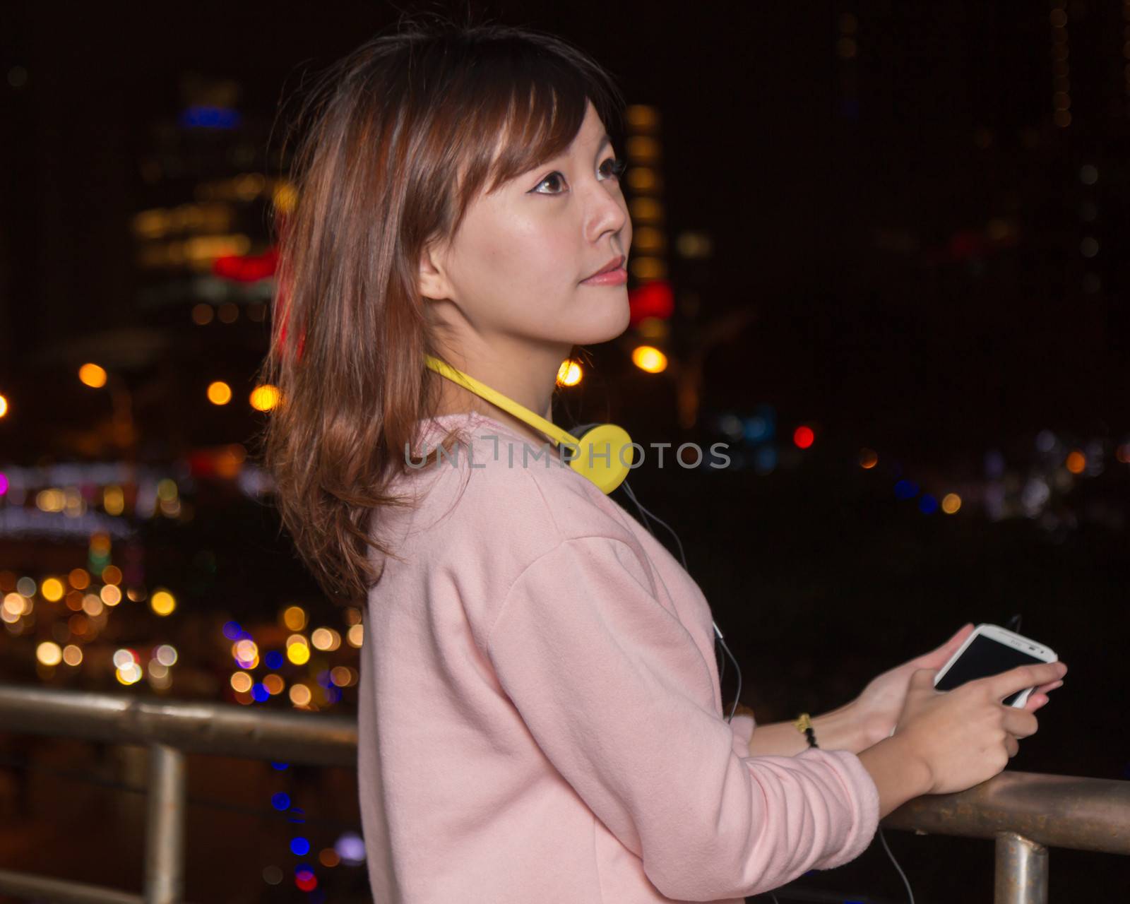 Beautiful Asian woman with smart phone and yellow headphones  by imagesbykenny