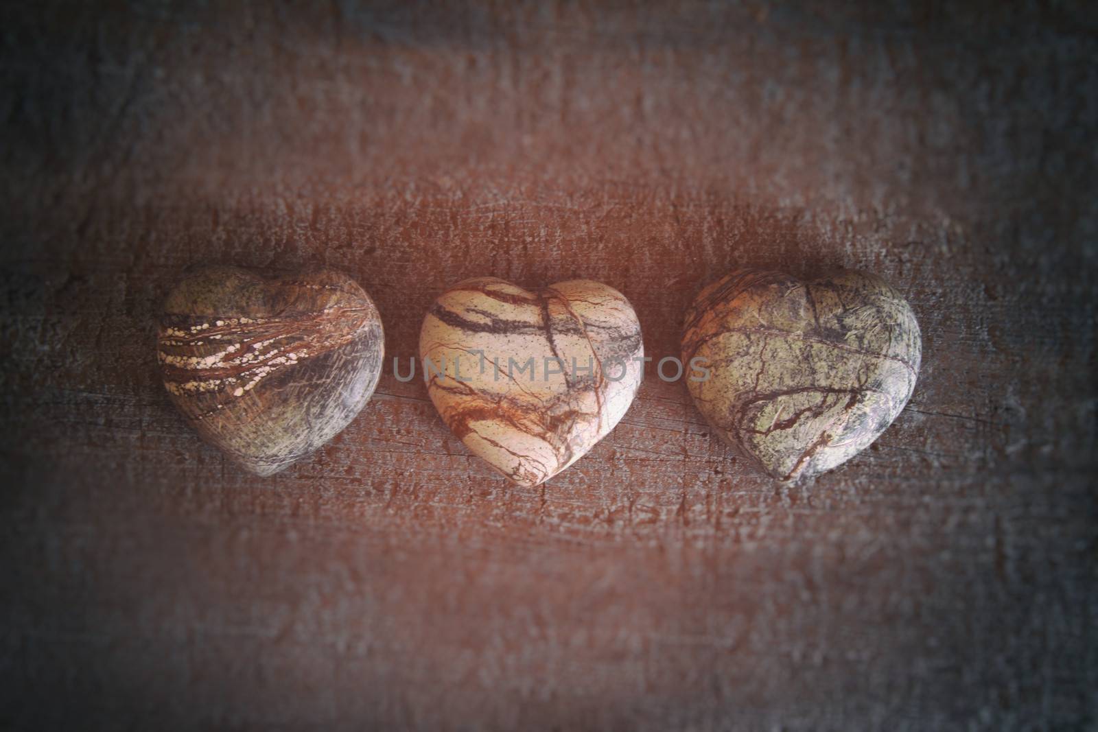 Three stone hearts on wood background