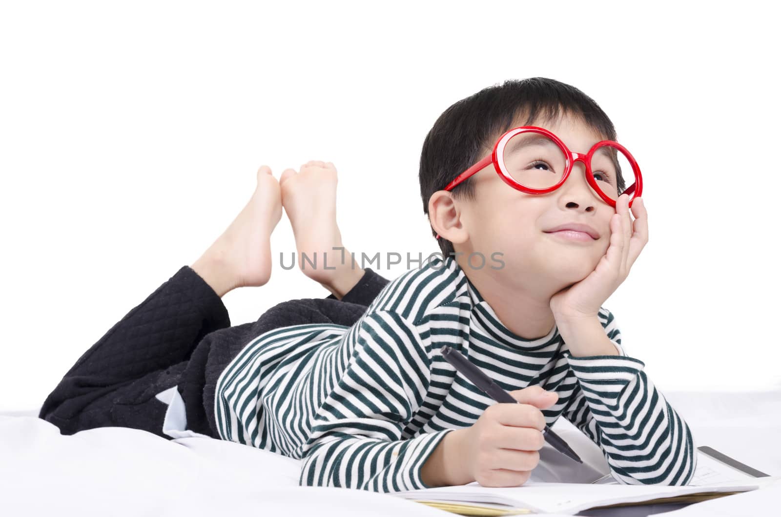 Smart child lying on bed  writing and thinking