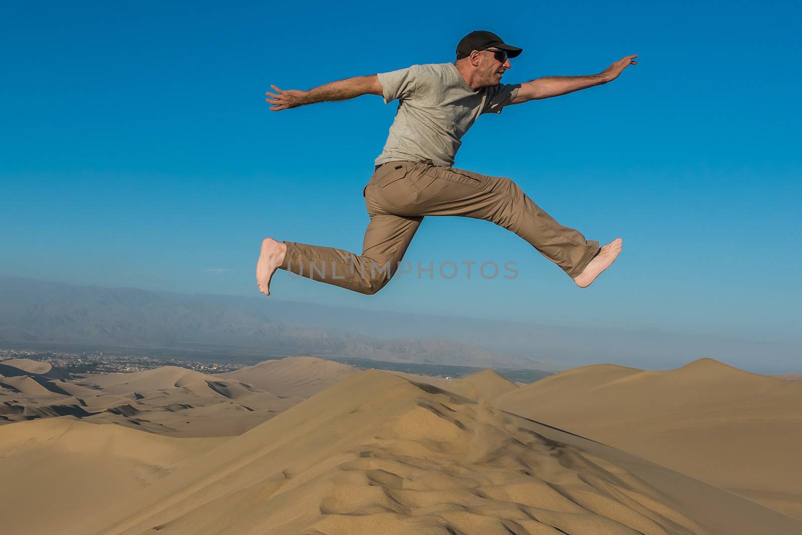 man jumping in the desert in the peruvian coast at Ica Peru