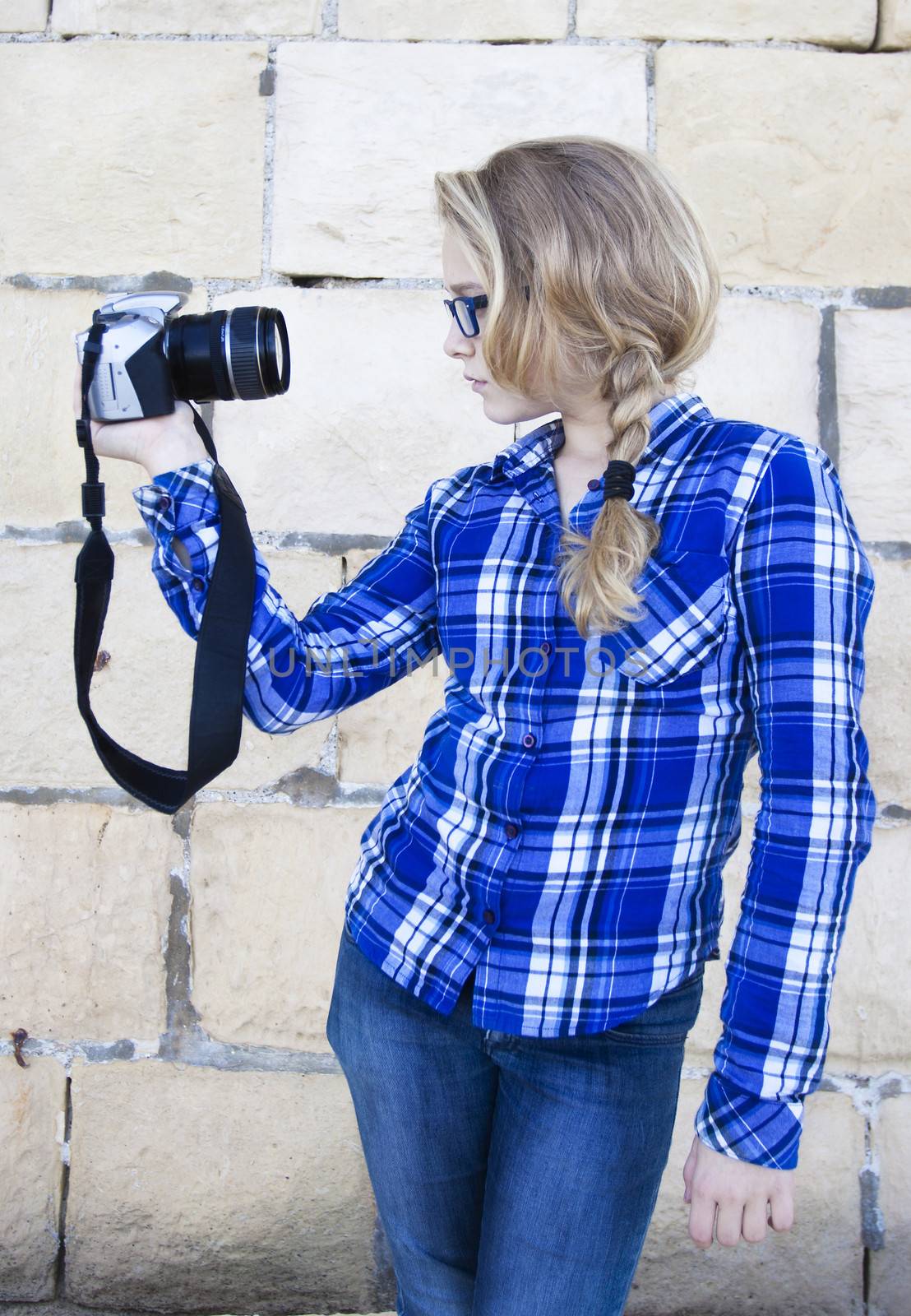 A modern youmg woman in profile holding up a digital camera, snapping a selfportrait