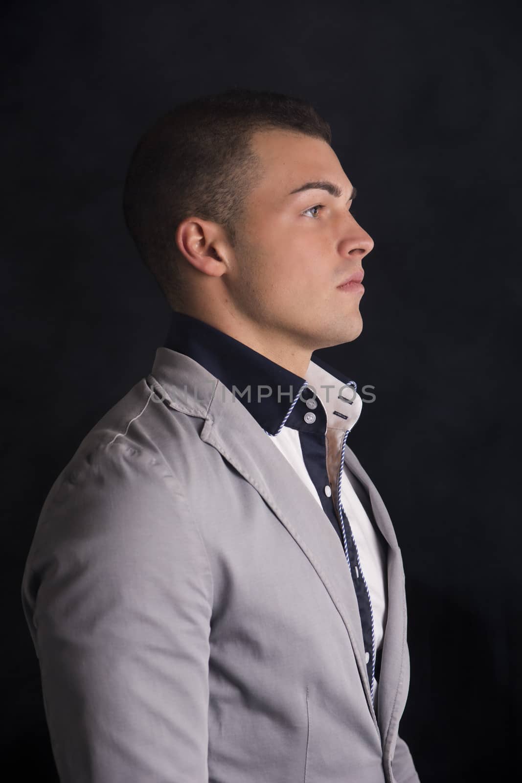 Profile view of elegant handsome young man with shirt and jacket, dark background