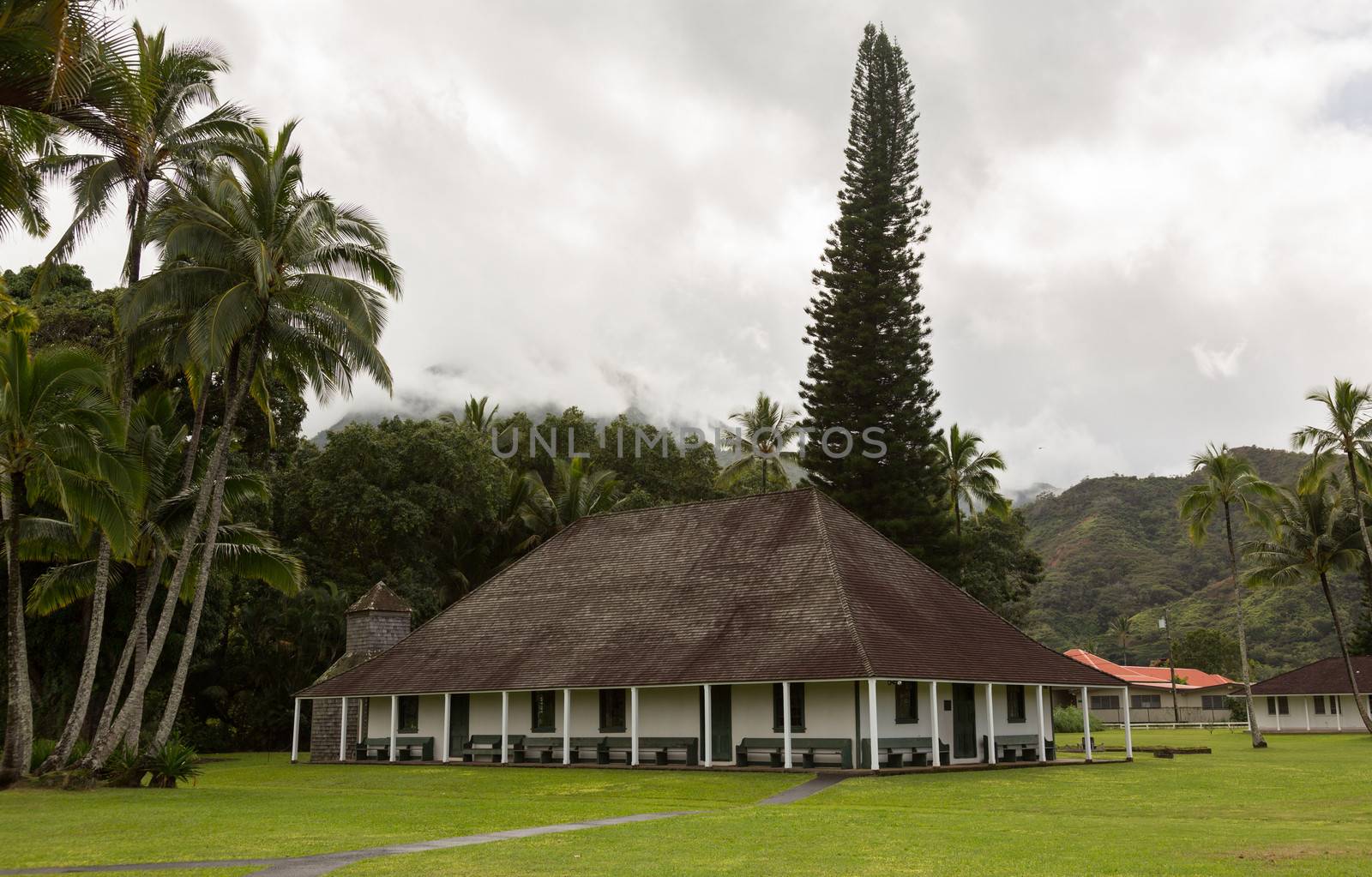 The old Waioli Huiia Mission building and hall in Hanalei Kauai with the Na Pali Mountains shrouded in mist in the background