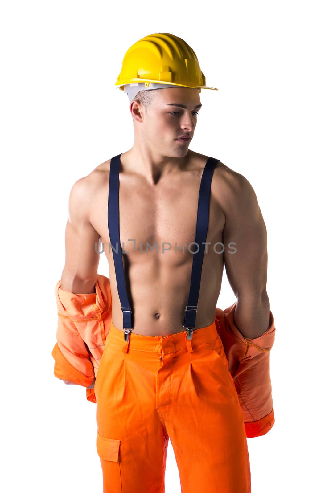 Handsome young construction worker taking off orange suit open on naked torso, wearing yellow hardhat
