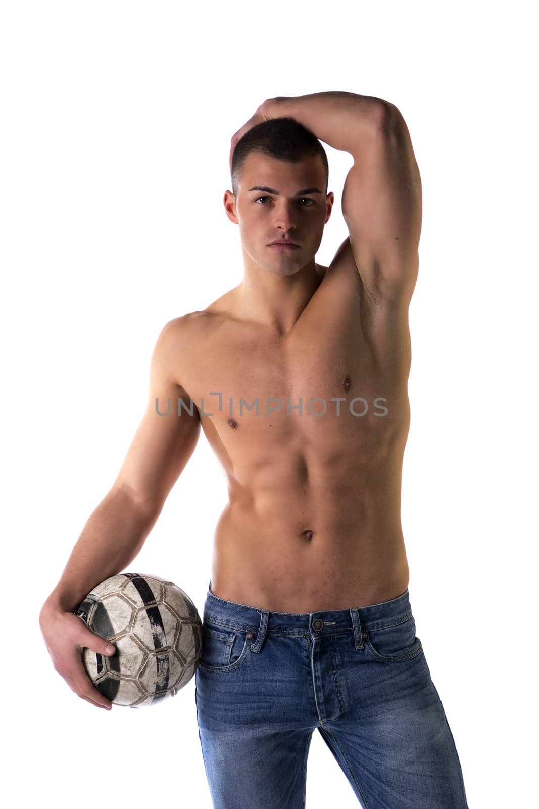 Shirtless football (soccer) player in jeans with ball standing, isolated on white