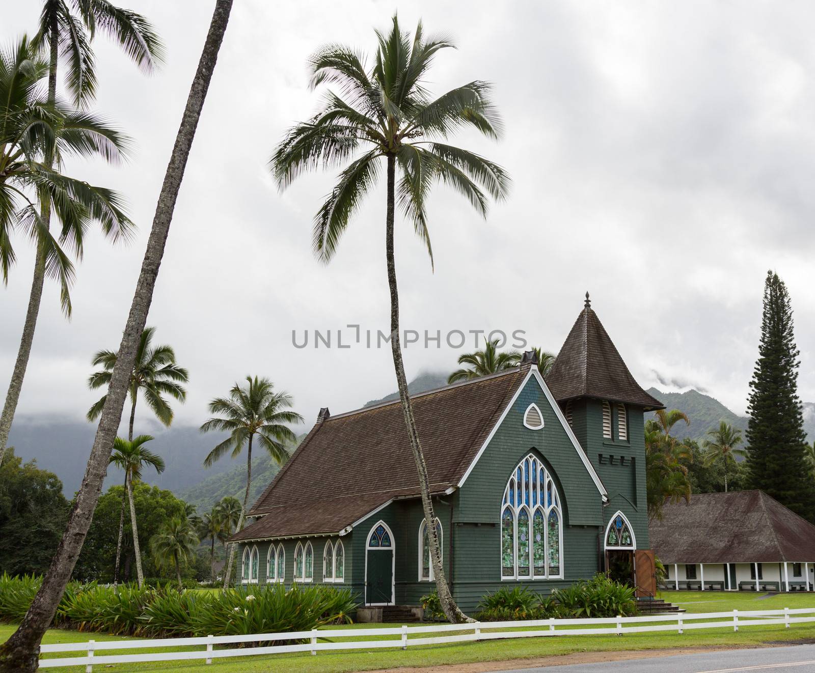 The old Waioli Huiia Mission church building and hall in Hanalei Kauai with the Na Pali Mountains shrouded in mist in the background