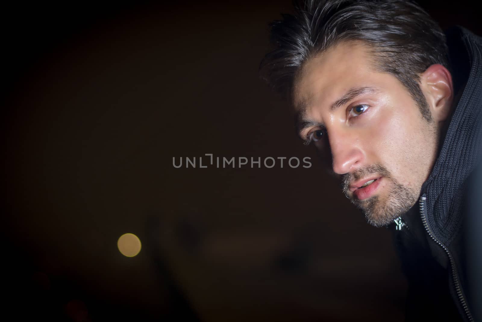 Attractive young man portrait at night, looking off camera