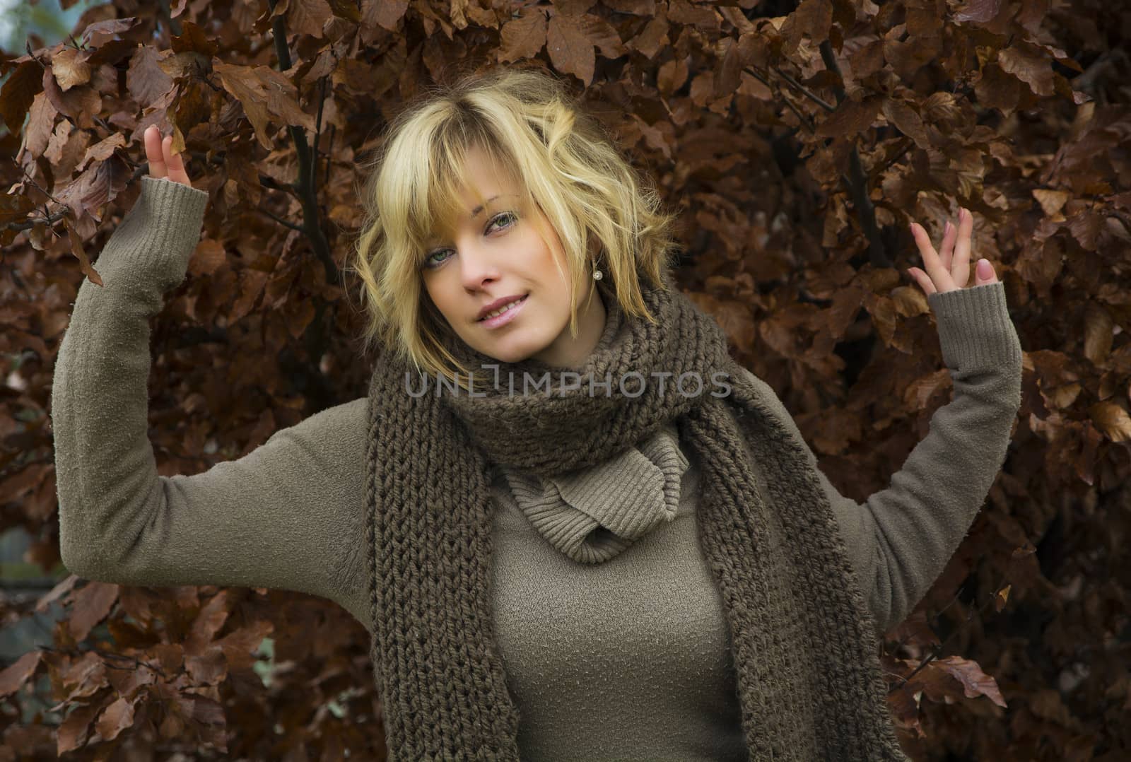 Attractive blonde young woman against autumn leaves wearing wool clothes