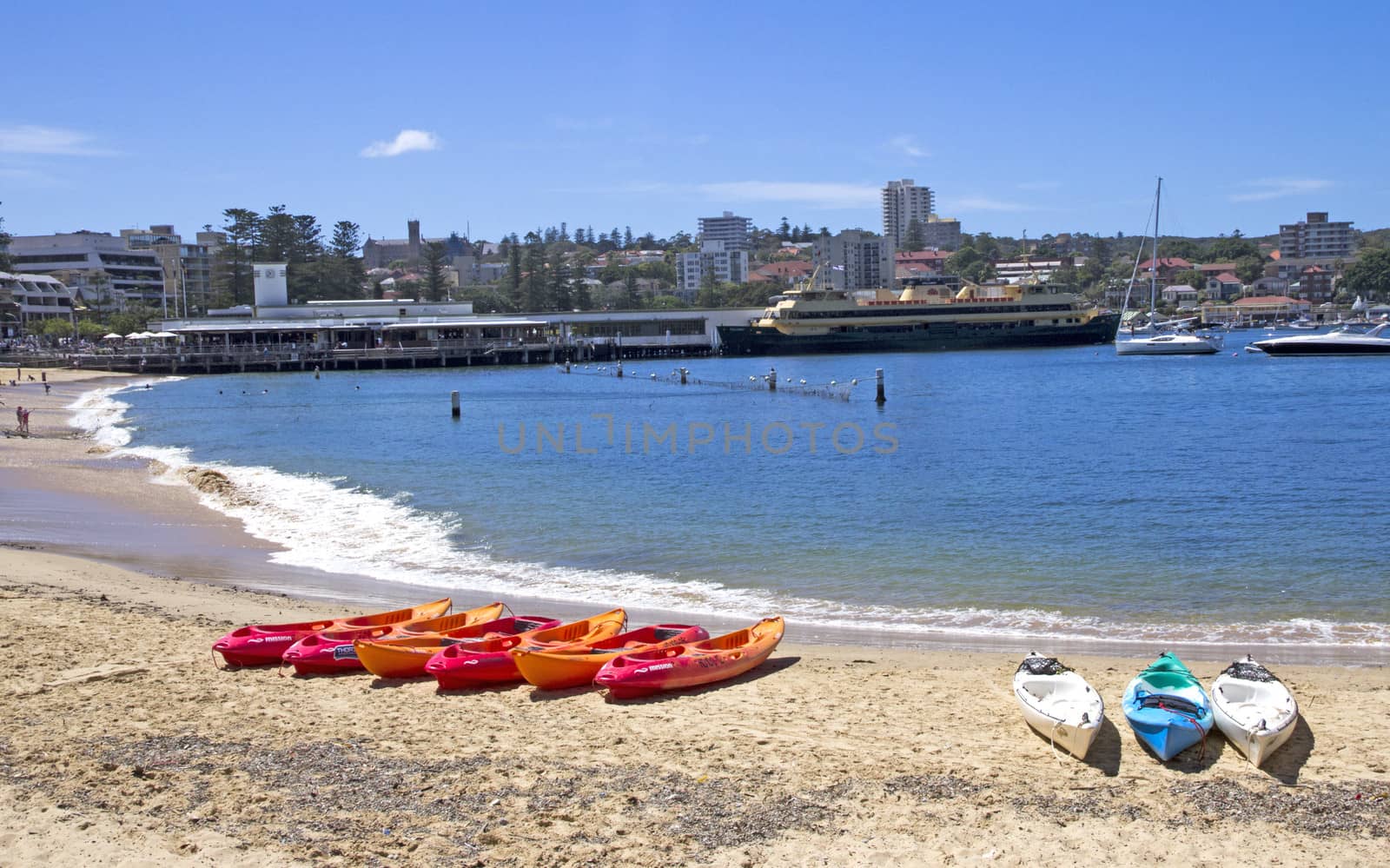 MANLY, AUSTALIA-DECEMBER 08 2013: Kayaks on Manly cove beach with the ferry in the background. Most people travel to Manly by ferry from Sydney's Circular Quay.