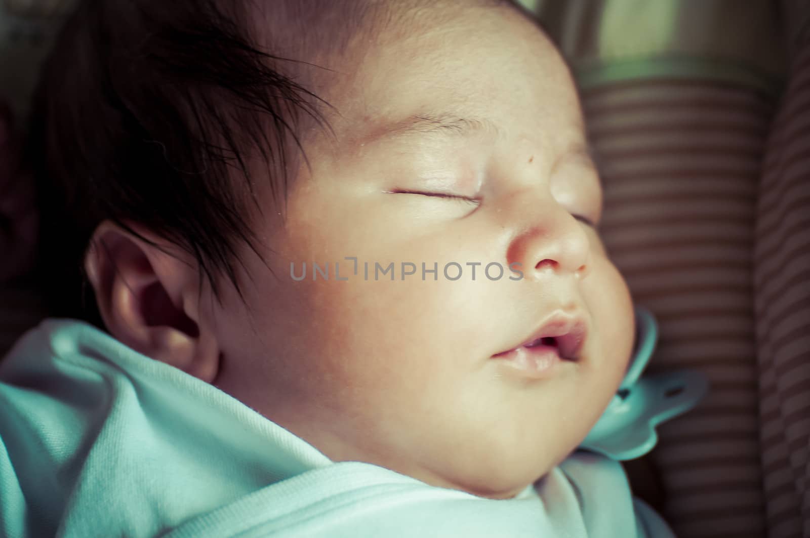 Newborn peacefully sleeping, picture of a baby curled up sleeping on a blanket