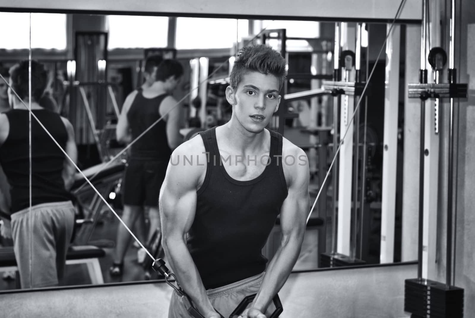 Teen bodybuilder working out with gym equipment by artofphoto