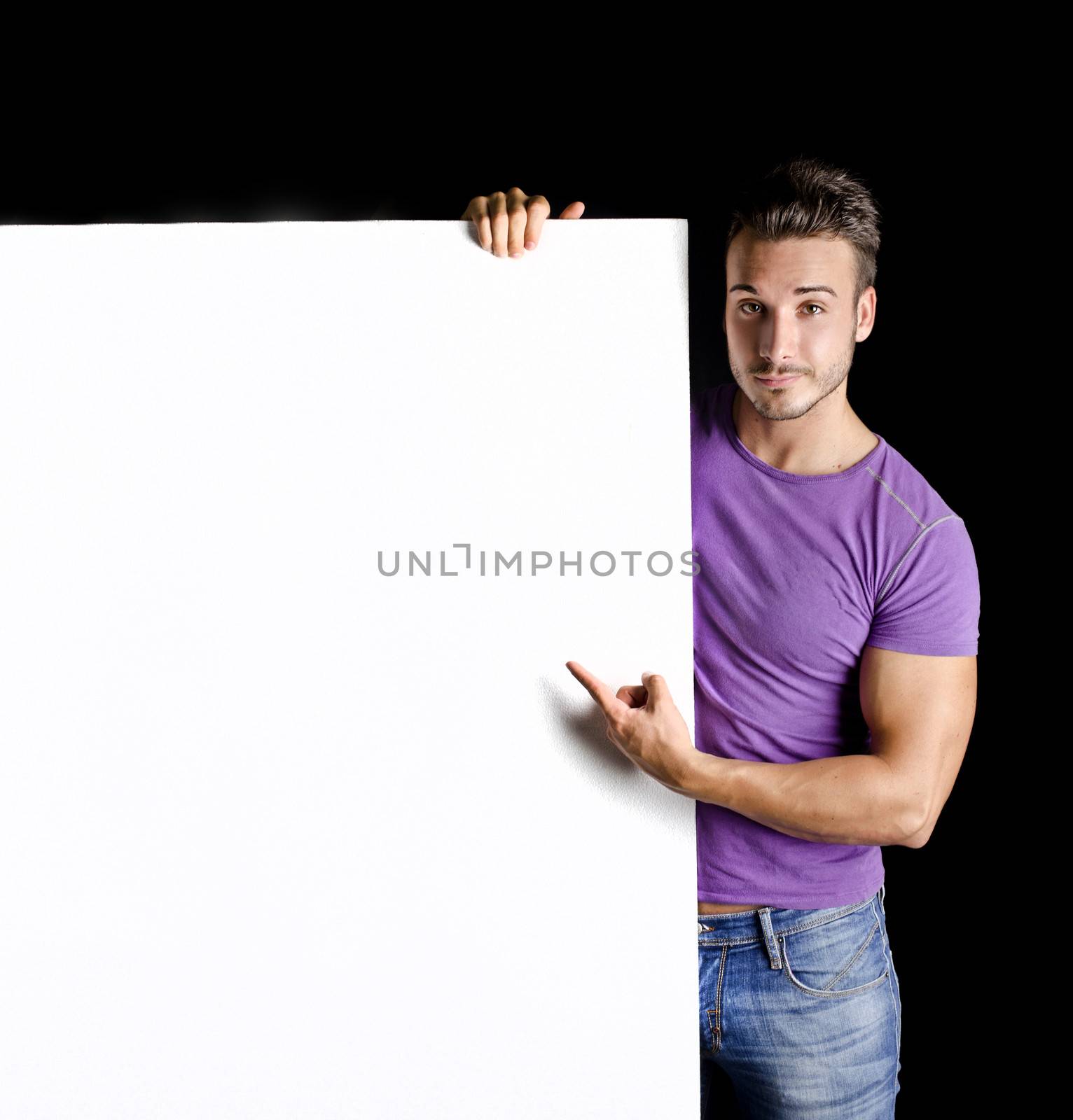 Handsome young man with large blank display or board, on black background
